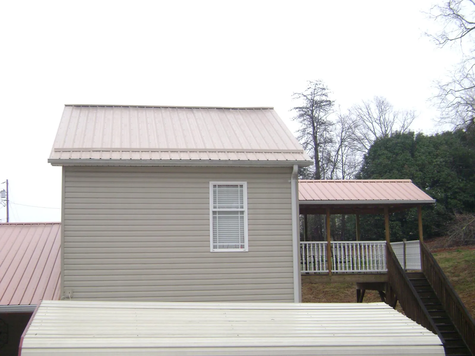 Tan metal roofs on a two story addition and attached porch, from a Roof Replacement job in Mineral Point